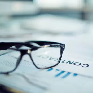 A pair of glasses rest on a contract